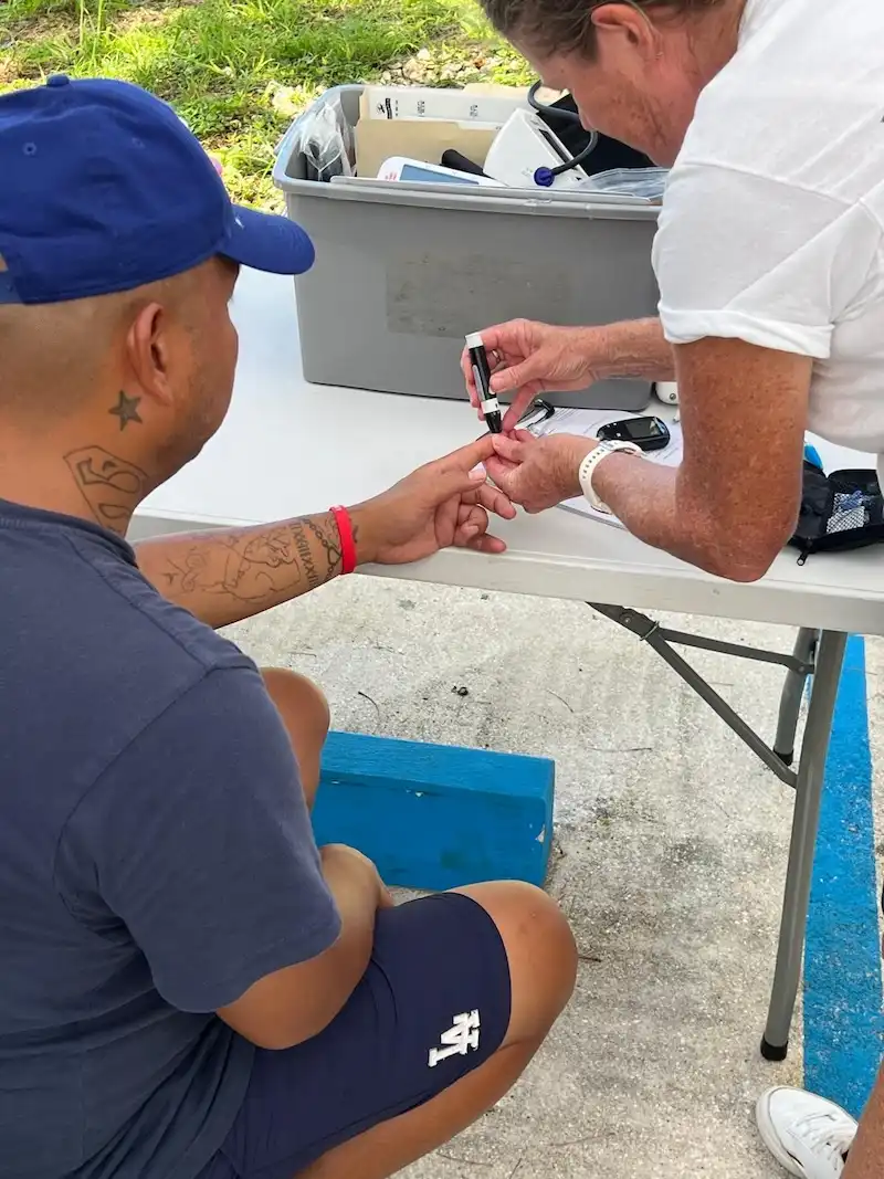 Healthcare worker performing a blood glucose test during a community health outreach in Guam